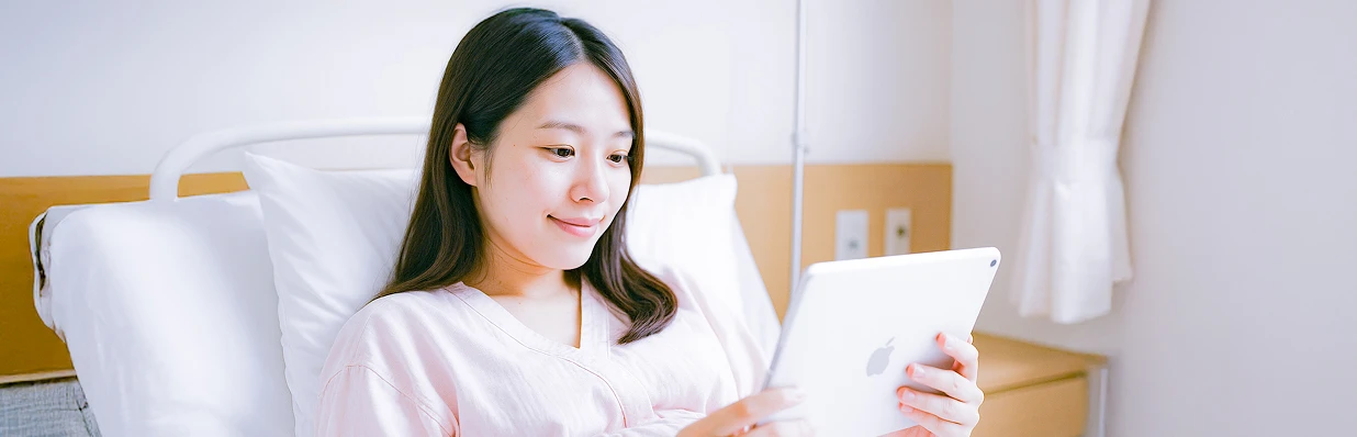 明るい病室でipadを見ている妊婦さんの様子