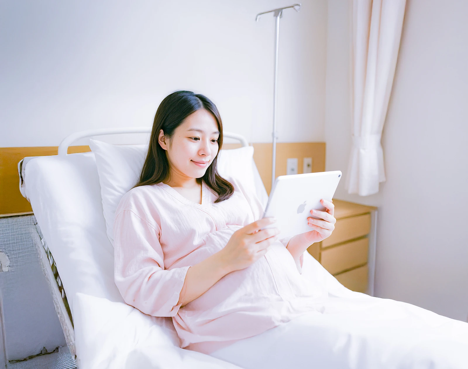 ベビーパッドベッドサイド - 入院されている妊婦さんがタブレットを見ている様子